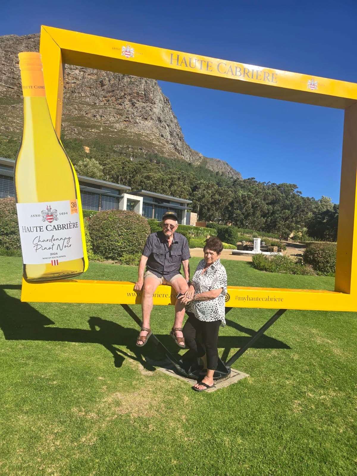 Couple sitting in the yellow Haute Cabrière frame in the vineyards