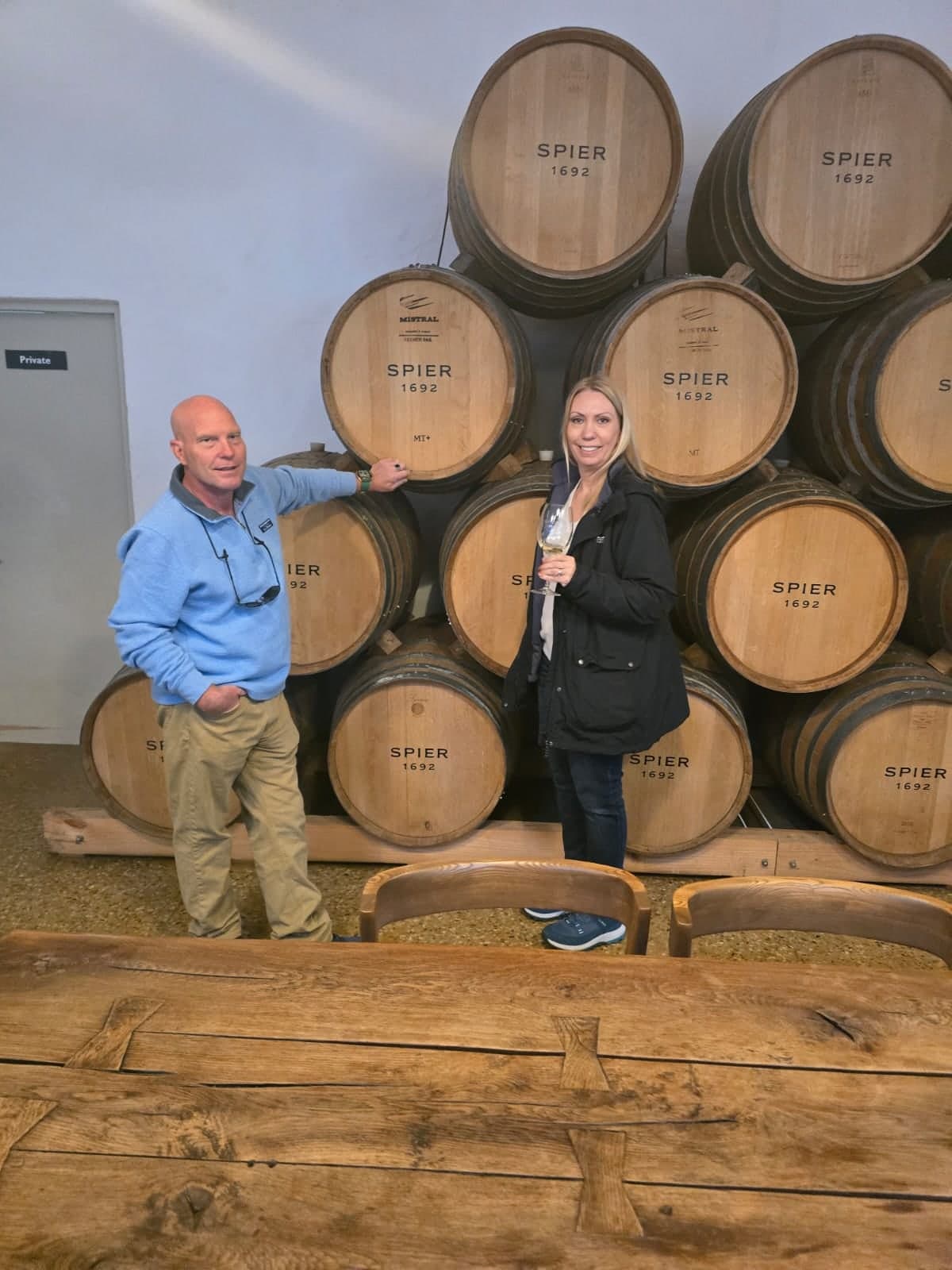 Couple with a glass of white wine in front of the Spier barrel cellar