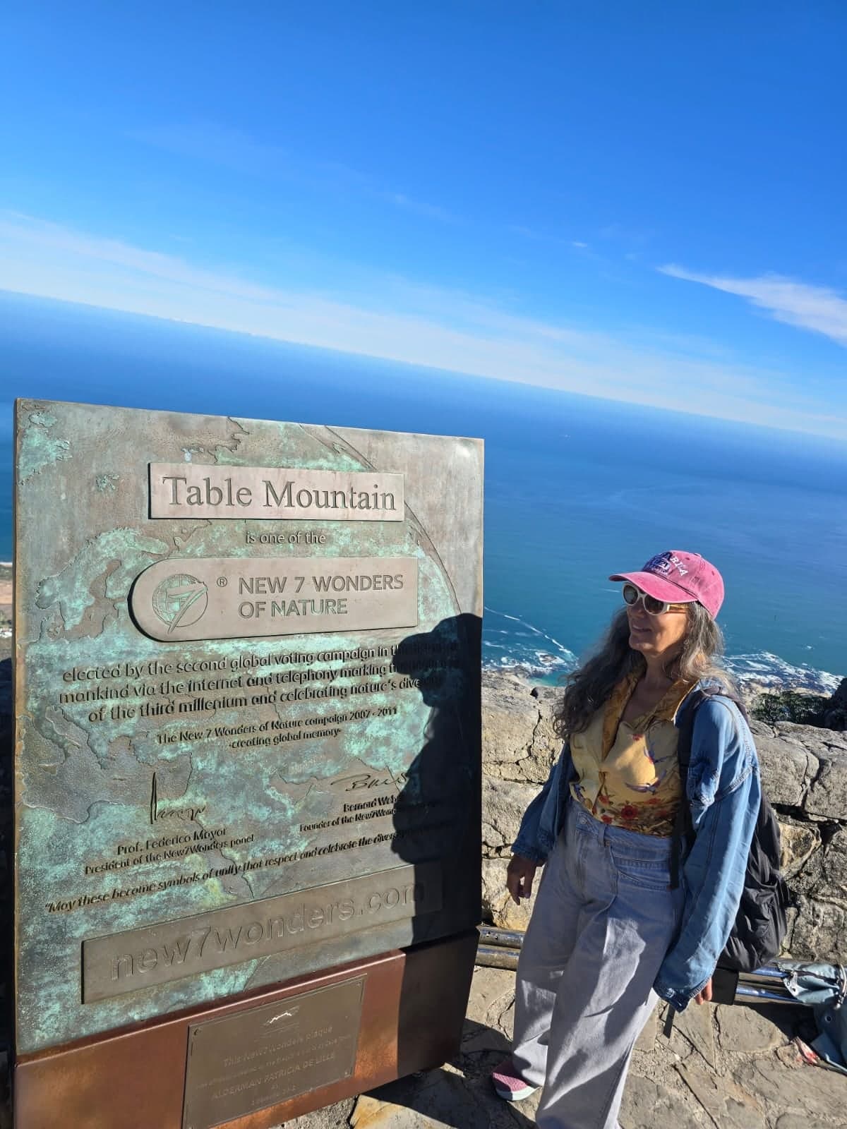 Guest beside the Table Mountain New 7 Wonders of Nature plaque at the summit